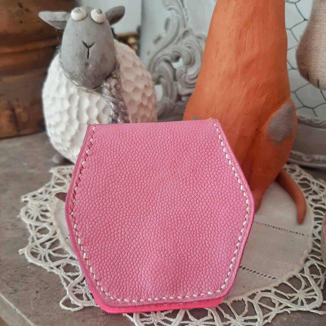 Porte -monnaie de forme hexagonale. Cousu à la main au point sellier avec du fil de lin dégradé rose/blanc. Il se plie en deux, et lorsque vous l'ouvrez, vous pouvez y glisser la monnaie dans l'ouverture en forme de coeur. Son cuir exterieur est un cuir rose grainé dit grain de caviar. Doublure intérieure cuir lisse couleur rose fluo.
