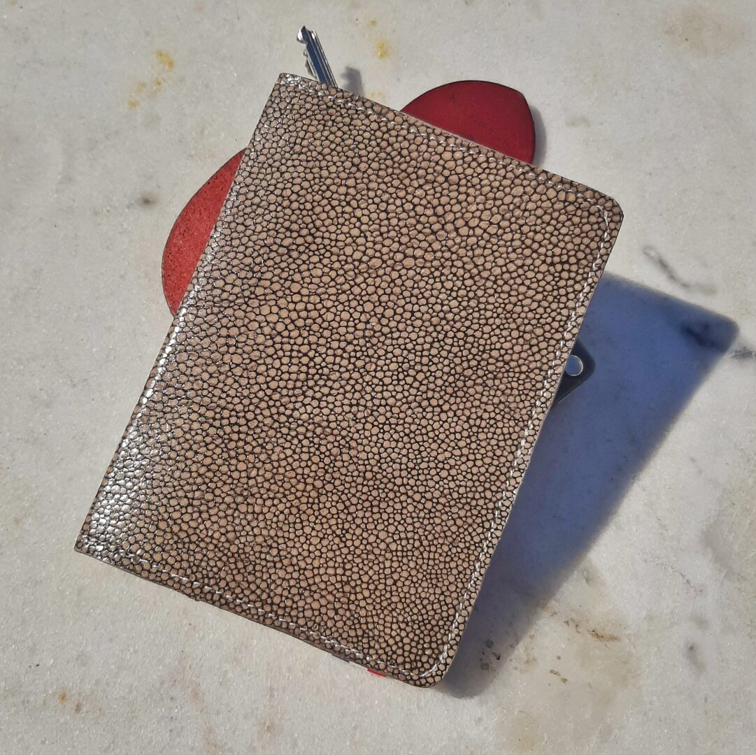 Porte-passeport en cuir grainé imitation galuchat, de couleurs beige et brun.