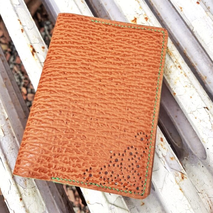 porte-passeport en cuir imitation cuir requin. Couture main au point sellier avec fil de lin vert. Motif ajouré sur le bas droit du porte-passeport, réalisé à la main avec des emporte-pièces ronds de différentes tailles.