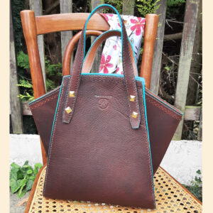 Sac cabas en cuir marron chocolat pull up (cuir gras) et grainé. Cousu main avec un fil de lin couleur turquoise. Finition des tranches teinture bleu turquoise.