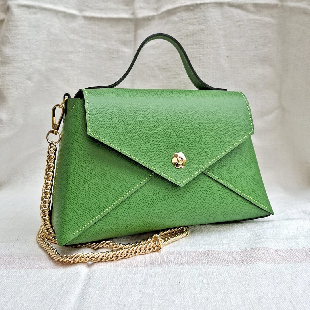 Sac à main enveloppe en cuir croûte de veau vert avec poignée, chaîne dorée amovible et fermeture fleur magnétique.
