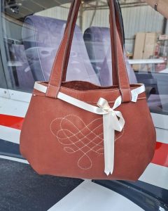 Vue de face d'un cabas en cuir pleine fleur avec motif géométrique cousu main et ruban satin écru
