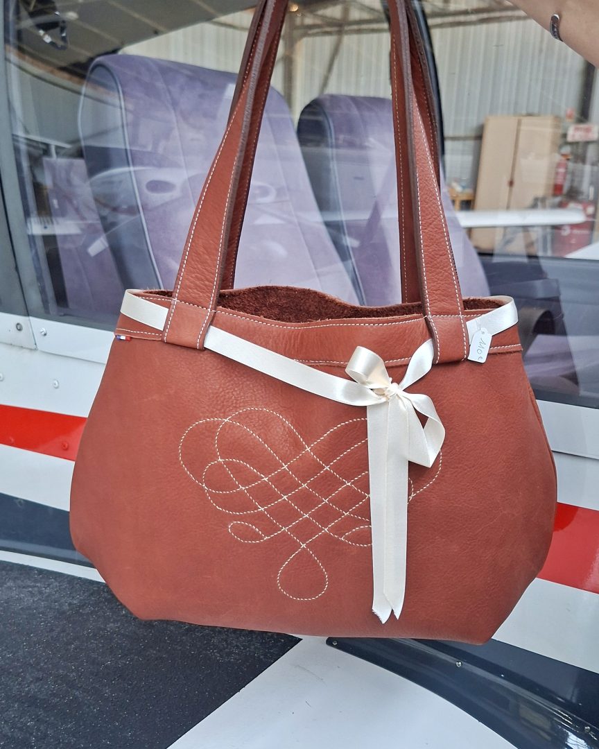 Vue de face d'un cabas en cuir pleine fleur avec motif géométrique cousu main et ruban satin écru